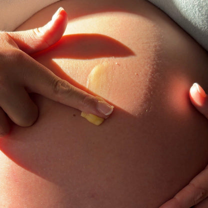 Hand applying a belly balm to a pregnant belly