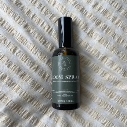 Glass room spray bottle on a bed spread.