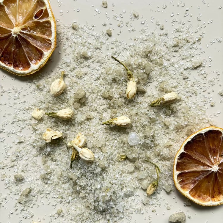 Dried lemons, jasmine flowers and bath salt mixture on a textured surface