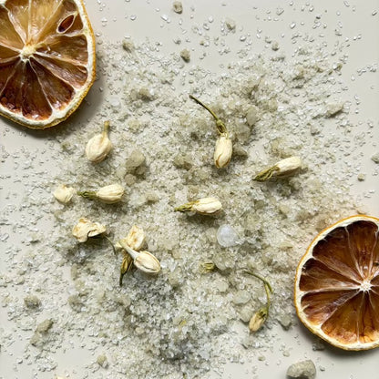 Dried lemons, jasmine flowers and bath salt mixture on a textured surface