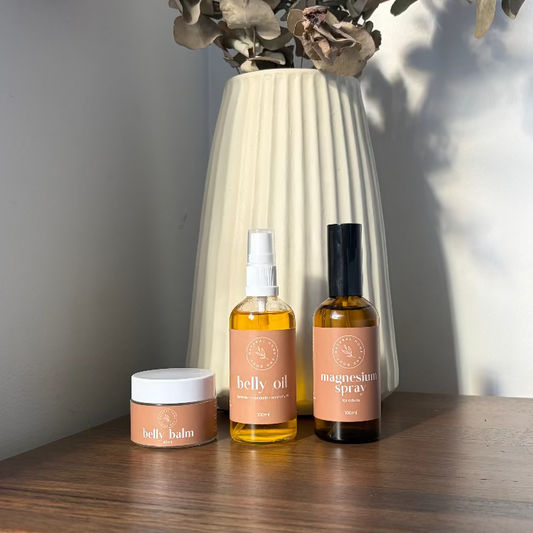 Three skincare products on a wooden surface with a vase and eucalyptus branches in the background.