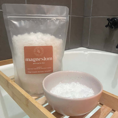 Magnesium. bath salts displayed on a   bamboo bath rack across a bath tub, with another bowl beside it with some salts on display.