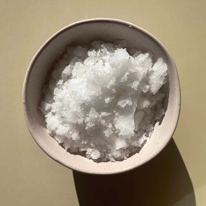 Magnesium bath salts product displayed in a bowl, on a beige background to show the texture of the salts.