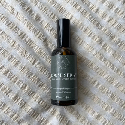 Glass room spray bottle on a bed spread.